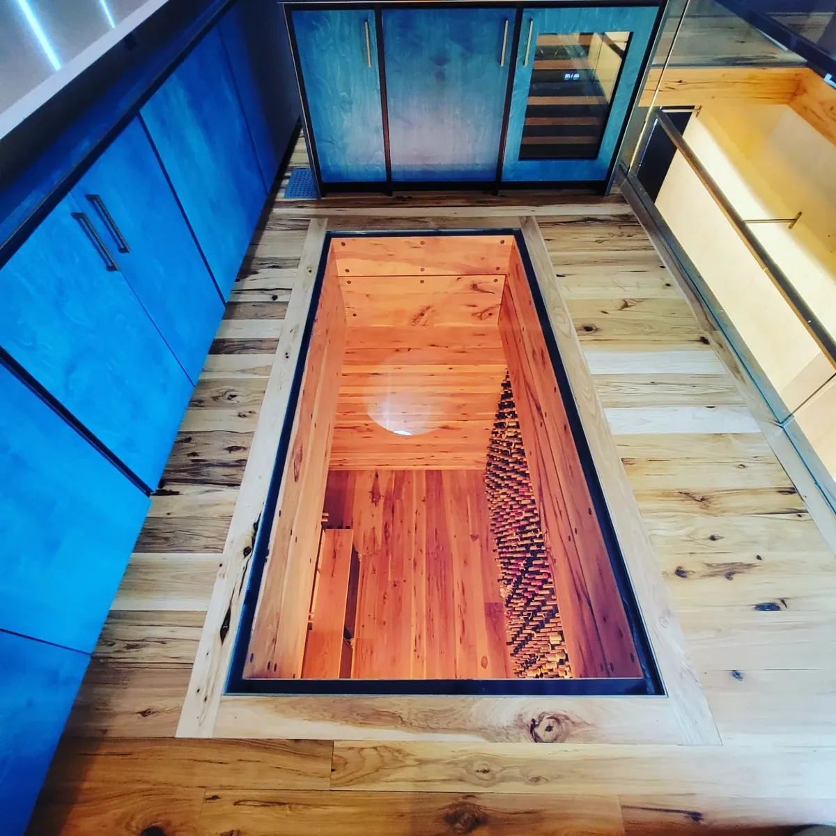 Cedar scene inlaid into a wide-plank floor beside blue cabinetry
